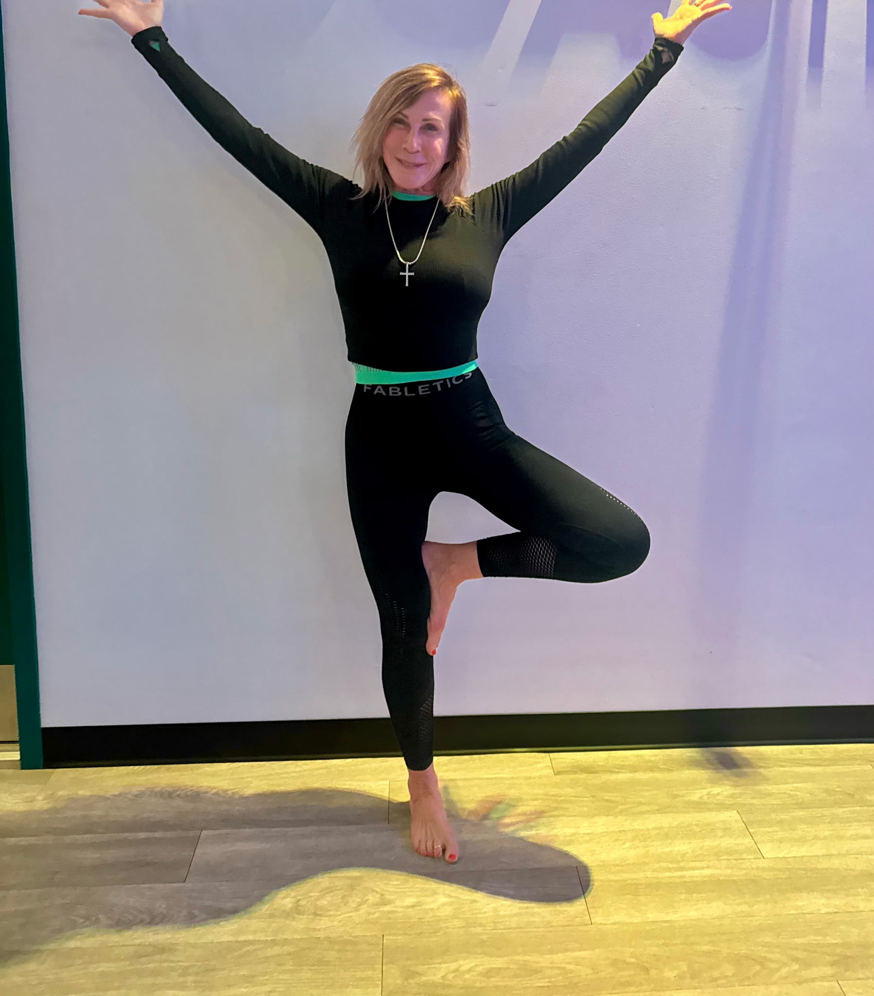 image shows Laura Kane in yoga tree pose, owner of One Body Fitness & Yoga in Little River, SC